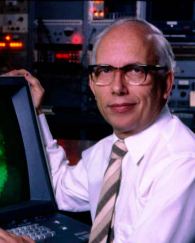 Man in glasses and a tie with his hands on a monitor