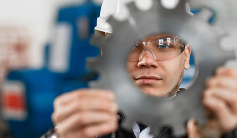 Factory engineer looking through a manufactured part.