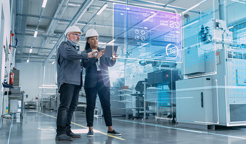 Operations photo showing two people on factory floor looking at analytics.