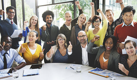 Learn and Improve photo showing a diverse group of employees around a table excited about improvement.