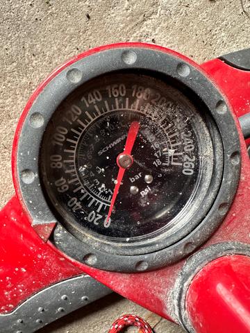 Close-up of a red bike tire gauge with a black dial. 