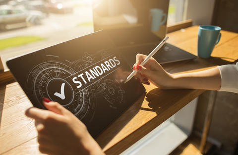 woman's hands holding a tablet with "standards" on the screen