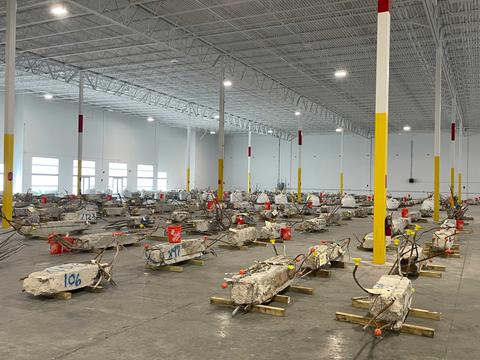 Concrete columns lay on their sides inside a warehouse with lots of space around each one.