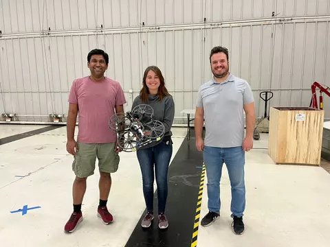 Team of two men and one woman holding a drone prototype