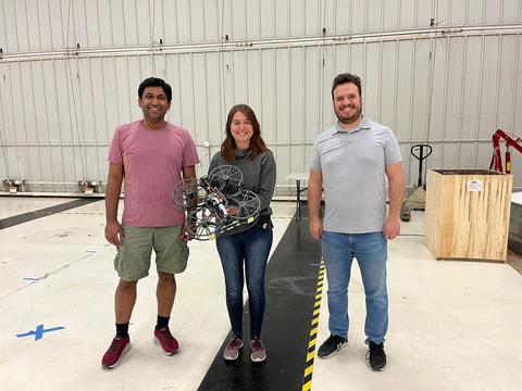 Team of two men and one woman holding a drone prototype