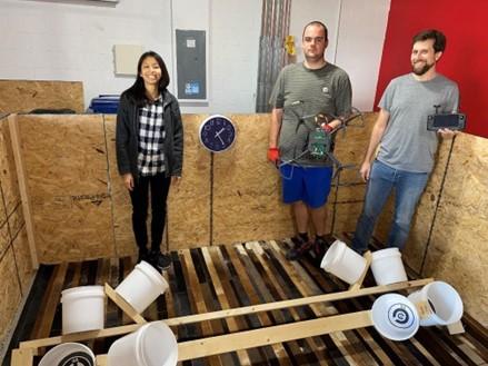 Two men and one woman standing in a demonstration room for their drone prototype.