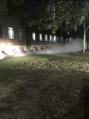 A building at night with a liquid nitrogen leak causing a creepy looking fog around the base of the building.