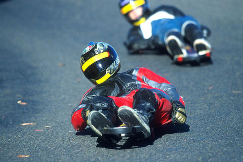 Two individuals luging downhill