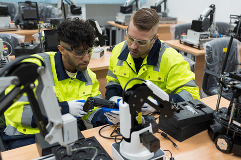 Two male engineers training on an AI Robot