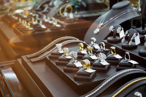 Rings and other gold jewelry items are displayed in a glass case. 