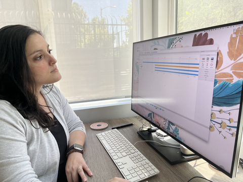 Carina Hahn sits at a workstation and looks at a computer screen.