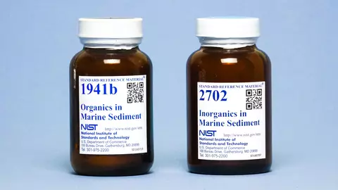 Photograph of two labeled amber bottles containing marine sediments.