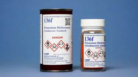 Photography of a labeled bottle containing orange potassium dichromate and labeled shipping tube for SRM 136f