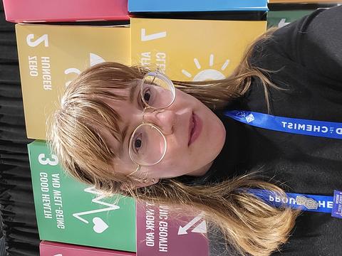 A headshot of Julie at the ACS Fall Conference 2022 in front of a wall decorated with the UN sustainable development goals