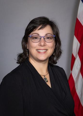 Studio head shot of Rachel Glenn with U.S. flag in background