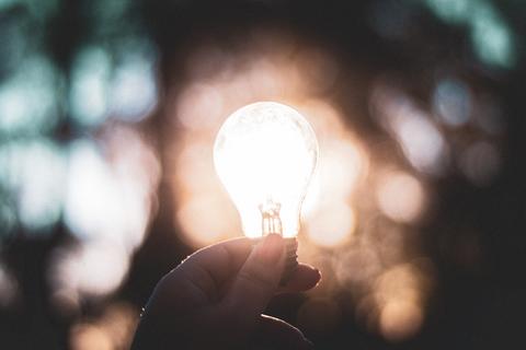 Hand holding a lit lightbulb