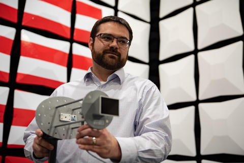 NIST researcher Jason Coder holds equipment while working in the National Broadband Interoperability Test Bed. 