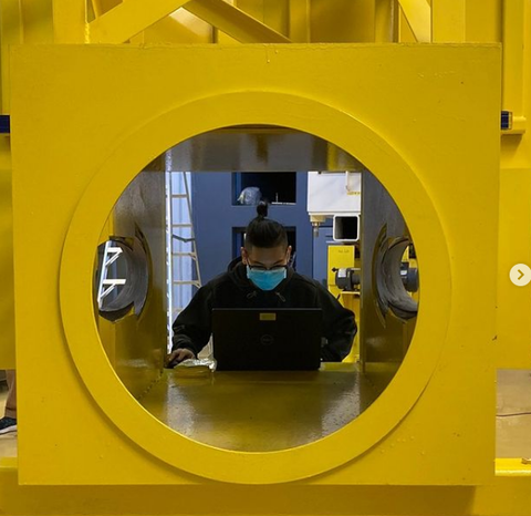 Employee works at a computer in NIST Center for Neutron Researcher, surrounded by large yellow window.