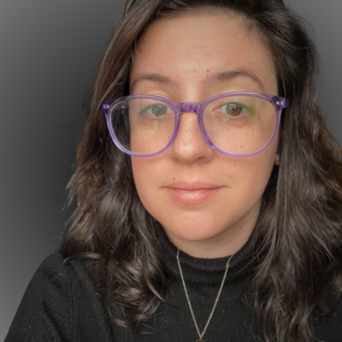 woman with brown hair and purple glasses wearing a black turtleneck