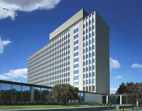 Narrow 11-story building rises into a blue sky.