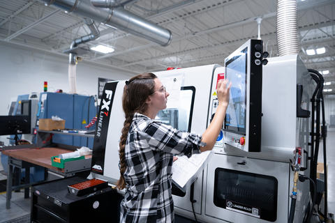 Young woman working on a machine in a manufacturing facility