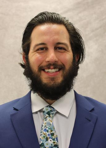 Headshot of Nathan Bryant, a man with dark brown hair, mustache, and beard, wearing a blue suit jacket, white dress shirt and a tie.