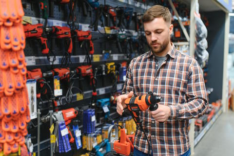 Man holding a drill in a hardware store