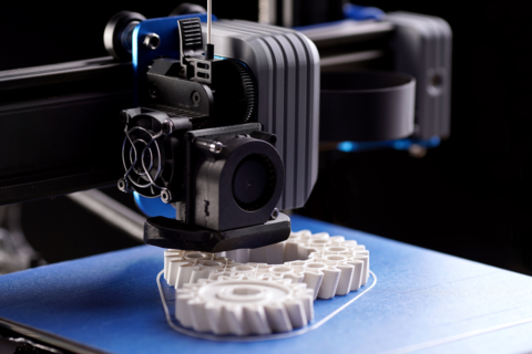 a 3D printer prints white gears using material extrusion