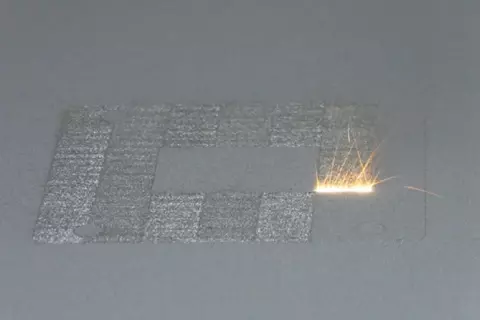 A high-power laser spot scans back and forth over a layer of cobalt-chrome powder on NIST's powder bed fusion additive manufacturing machine. Where it touches, the powder melts and fuses to underlying layers until a fully dense 3D metal part is formed. The laser travels back and forth so fast that, in this still image frame, it appears to form a white hot stripe about 10 millimeters wide.