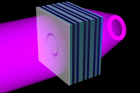 A schematic shows an opaque sheet with a ring-shaped opening layered over the left side of the metamaterial flat lens. Ultraviolet light shines from the left side of the metamaterial, through the ring-shaped opening, to the other side of the lens, where it's projected as a 3D ring of light.