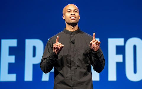 Tucker Bryant speaks on a stage in front of an audience.