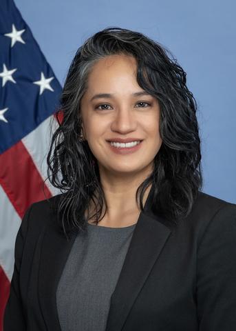 woman in front of blue background with US flag