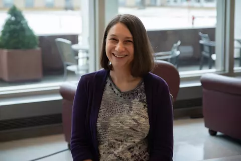 Julie Haney poses smiling for a casual portrait in the NIST library. 