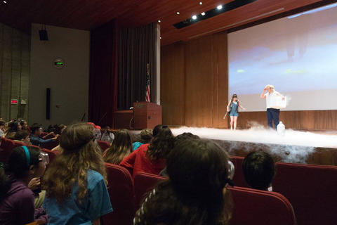 Woman doing a science experiment with dry ice on a stage