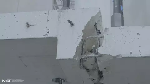 Close-up view of large crack in white concrete slab, with rebar showing.