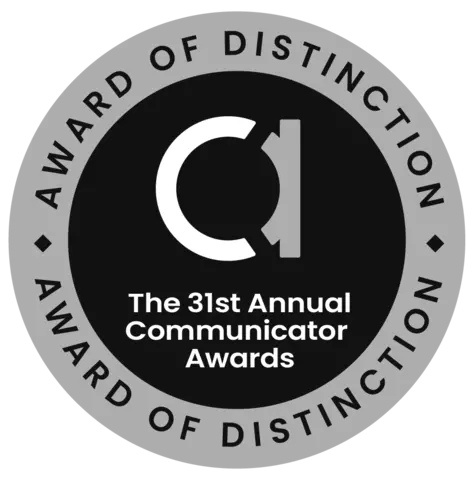 Round badge. Inner circle: fancy lowercase "A". Words: The 31st Annual Communicator Awards. Outer ring: Award of Distinction