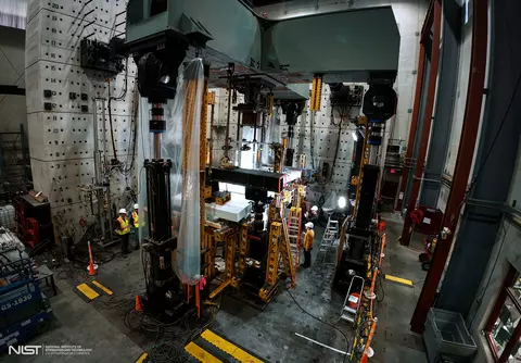 High-ceilinged lab space holds large pieces of equipment surrounding concrete slabs.  