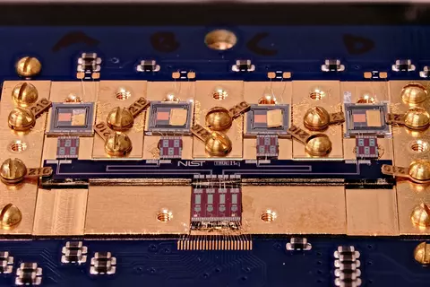 Circuit board with various square chips and gold screws. Small letters in the center say: NIST True Bq.