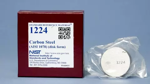 image of a brown box with a label that reads Standard Reference Material 1224 and a silver metal disk next to it with a stamped numbers 1224 on the disk