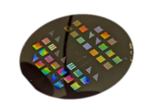 Black disk has multicolored squares and triangles on its surface. 