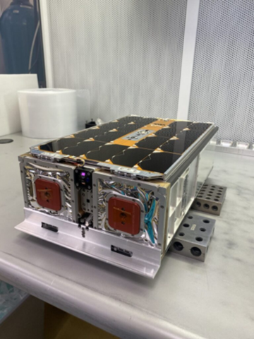 A rectangular device with wiring and various connections sits on a metal lab table. 