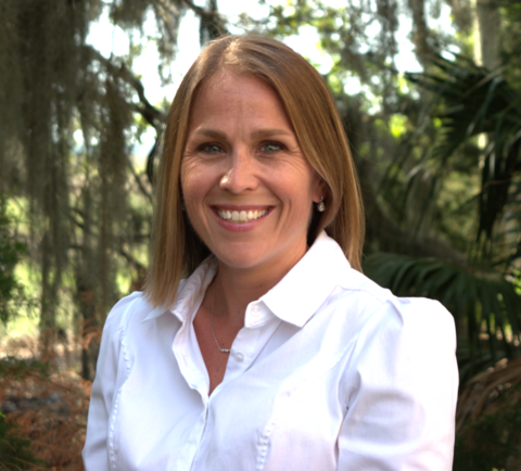 Debra Ellisor, a woman with medium length blonde hair, wearing a white collared shirt, smiling for a photo outside.