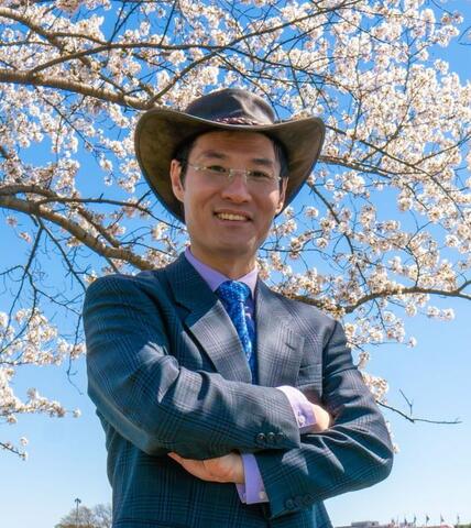 Dr. Raymond Sheh in front of cherry blossom trees near the Washington Monument in Washington DC. 
