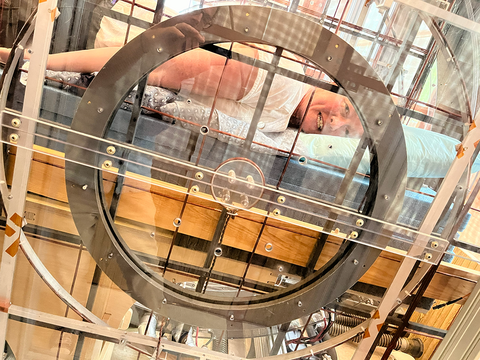 Woman is seen laying on her stomach through the translucent panel of an experimental medical device.