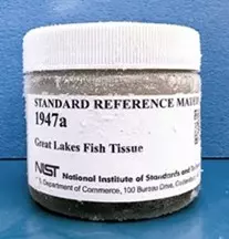 glass jar container with a white cap and white label that reads "Standard Reference Material 1947a great lakes fish tissue"