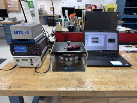 The photo shows the entire ENTR_v2 measurement setup that was recently deployed for field testing to Nellis Air Force Base. ENTR_v2 along with electronics and a laptop for controlling the system are depicted. A commercial red colored torque screwdriver is shown as an example of a tool which can be calibrated by ENTR.