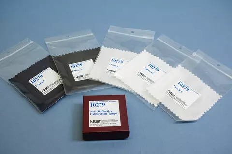 Five fabric swatches in clear plastic bags labeled 10279 are arrayed around a box labeled 99% Reflective Calibration Target. 