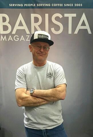 Greg Scace poses in front of a Barista Magazine banner made to look like he's on the cover.
