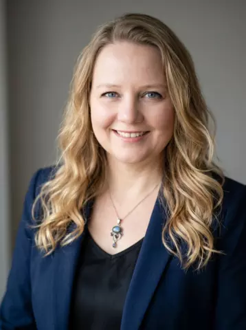 Headshot photo of Katherine Hall with a navy blazer and stone necklace