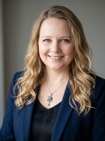 Headshot photo of Katherine Hall with a navy blazer and stone necklace